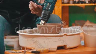 陶工正在用建筑吹风机烘干一个陶碗